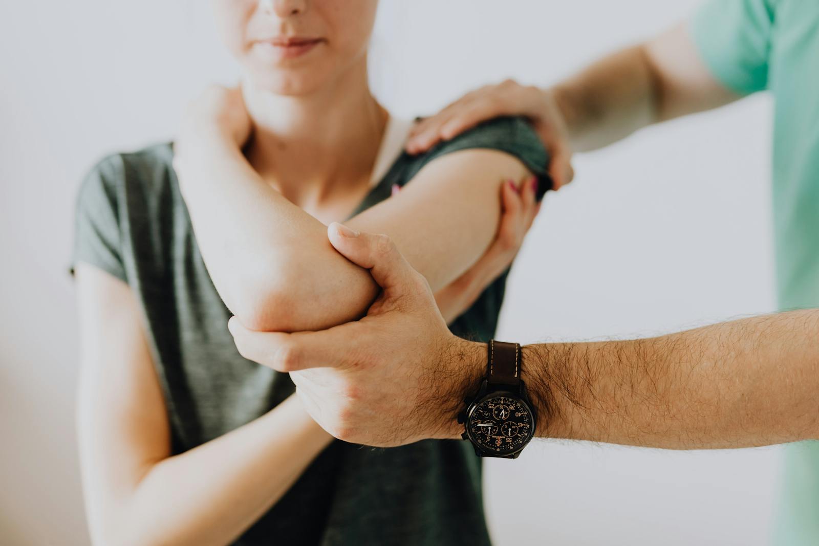 Fisioterapia Fénix Cádiz - A chiropractor adjusting a patient's arm in a clinic setting, focusing on health and care.